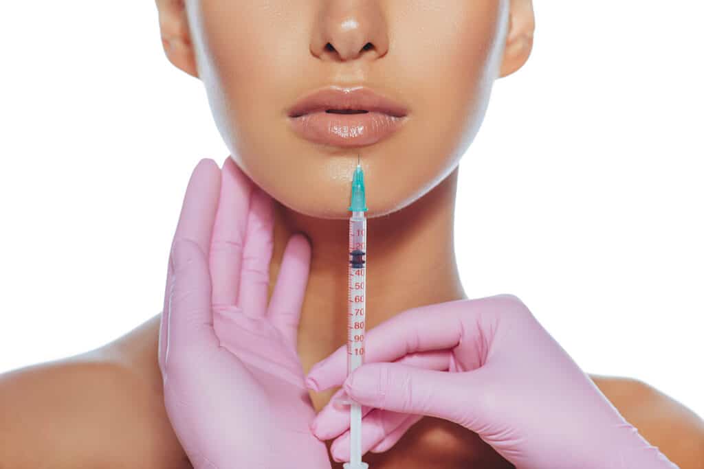 Syringe near womans mouth, injections for increase lips shape