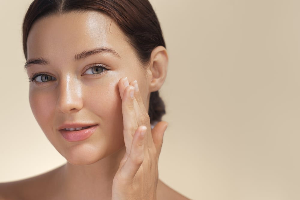 A woman with her hand on her cheek smiling after a Co2 fractional resurfacing treatment