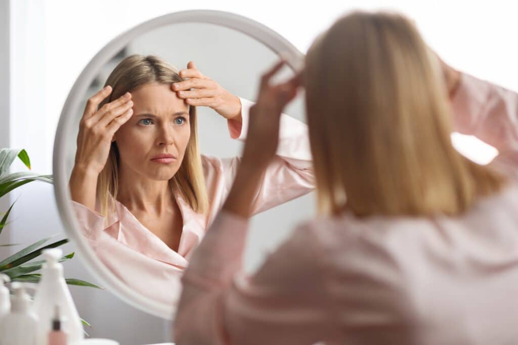 A woman looking in the mirror after Pellevé® treatment for facial skin tightening