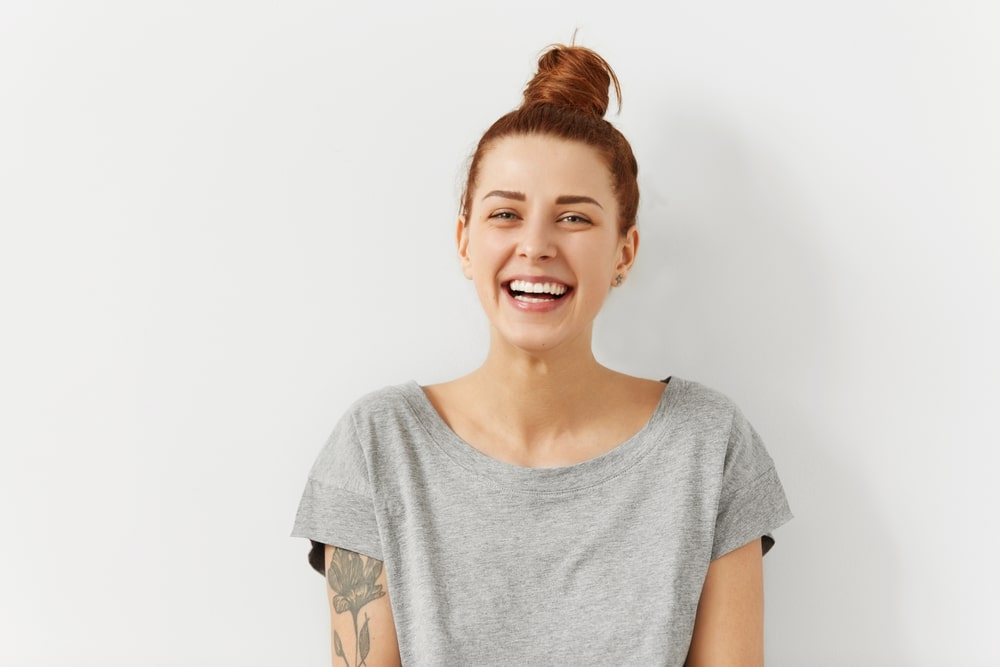 A woman with a tattoo on her arm smiling
