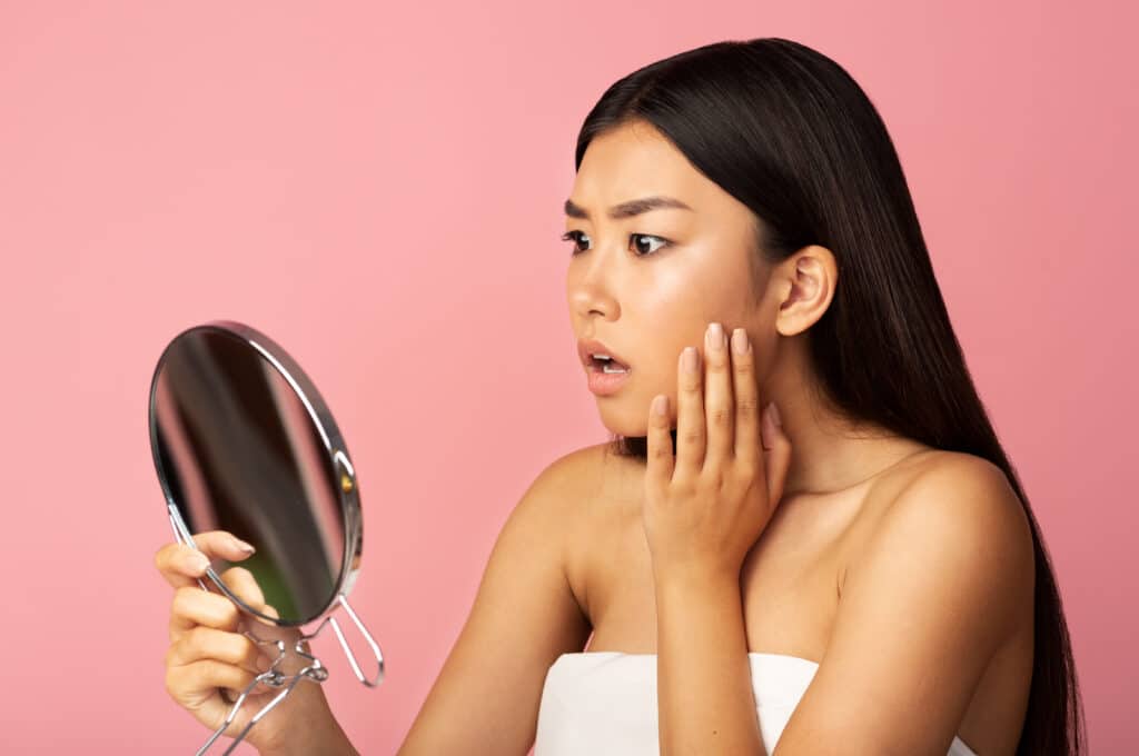 A woman looking at her facial veins in the mirror